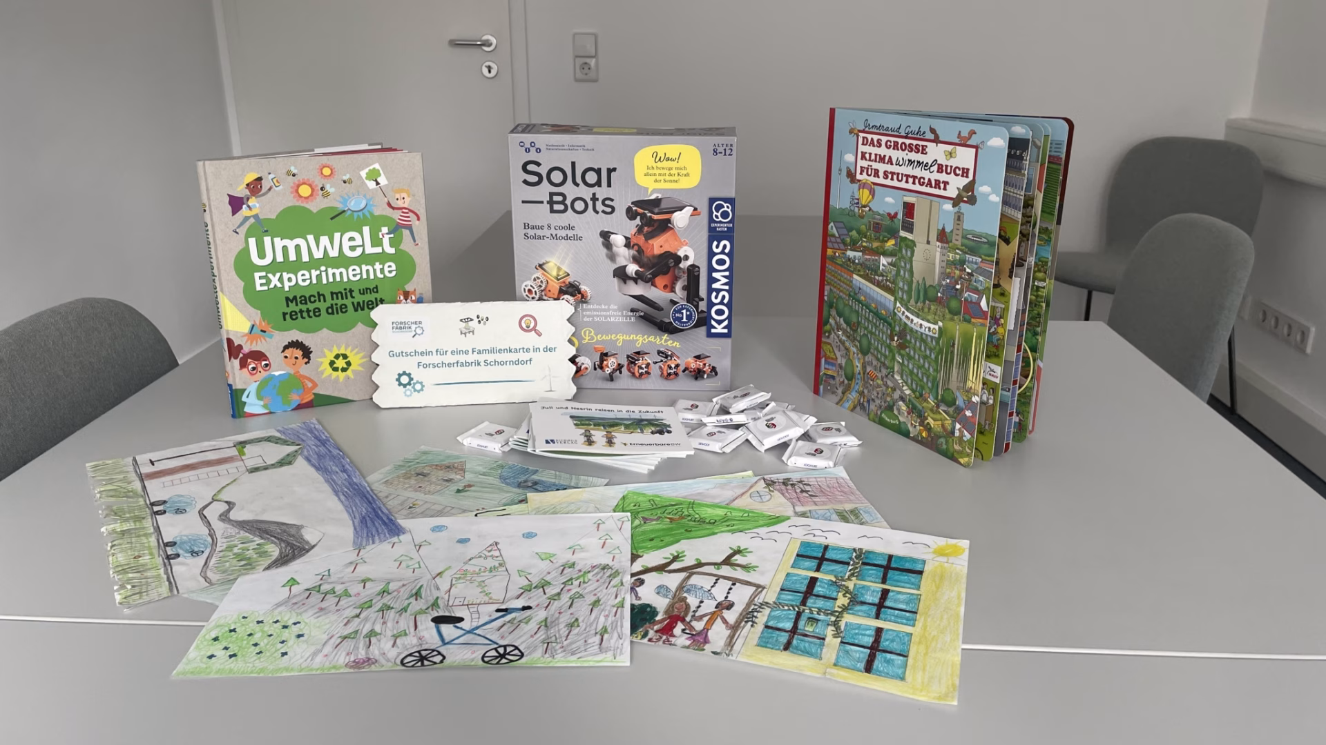 Auf einem Tisch liegen verschiedene Gewinnpreise für Kinder sowie ein selbst gestalteter Gutschein und bunte Kinderzeichnungen.