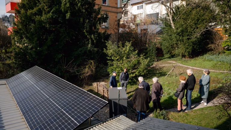 Menschen stehen in einem Garten vor einer PV-Anlage