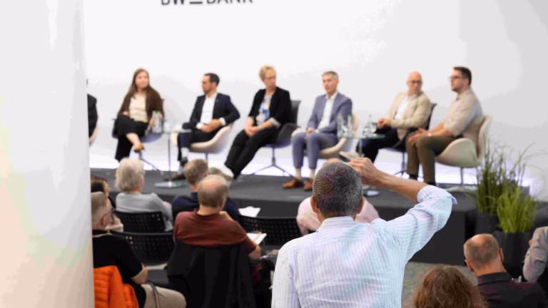Eine Person aus dem Publikum stellt dem Podium eine Frage