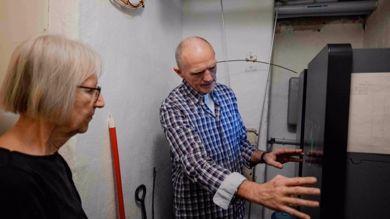 Eine Frau und ein Mann stehen in einem Keller vor einem Batteriespeicher
